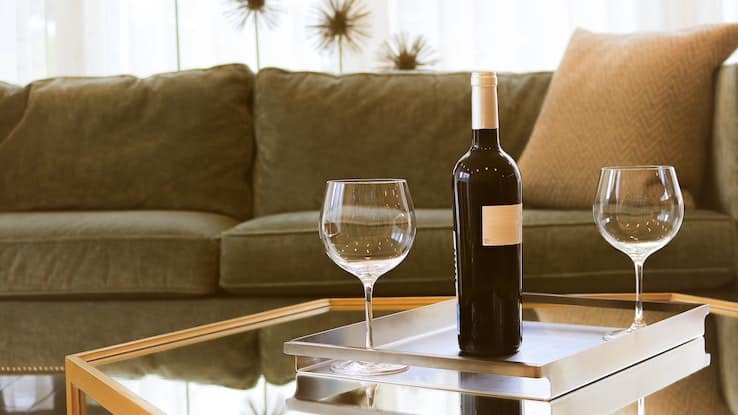 wine tasting with bottle of wine and two wine glasses on a living room table