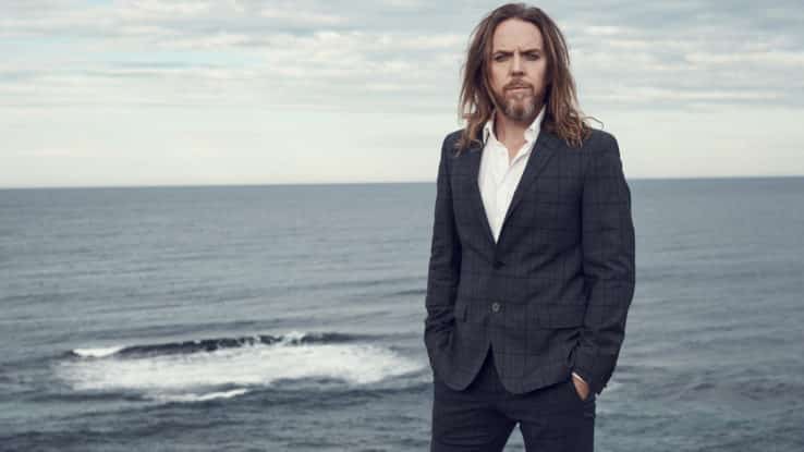 Tim minchin livestream concert image featuring tim standing in front of the ocean, photographed by Damian Bennett